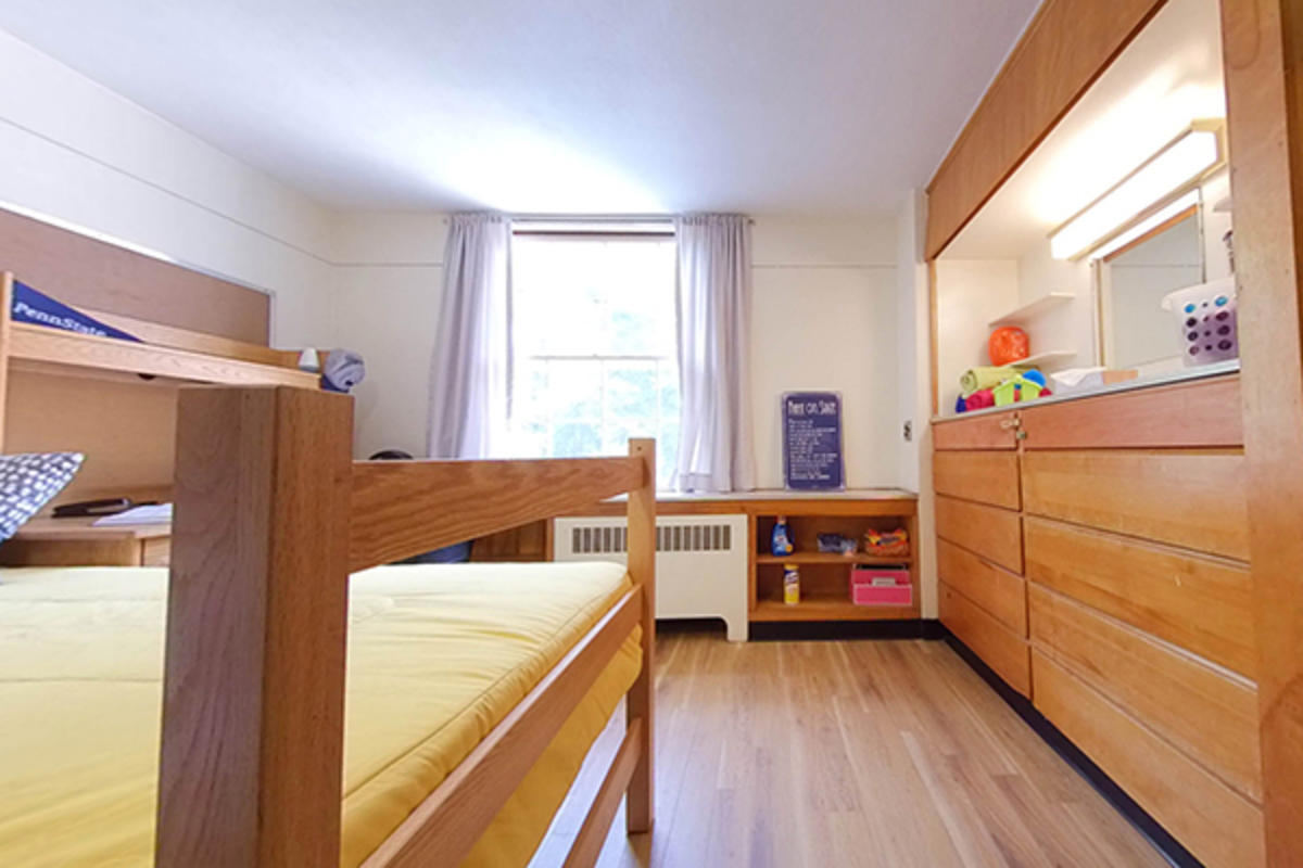 A well-organized dorm room with wooden furniture, storage, and a bed.