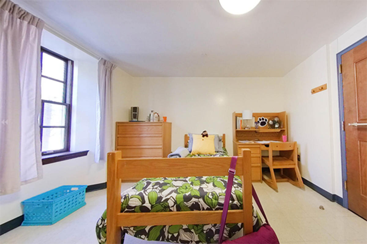 A well-organized dorm room with wooden furniture, storage, and a desk.