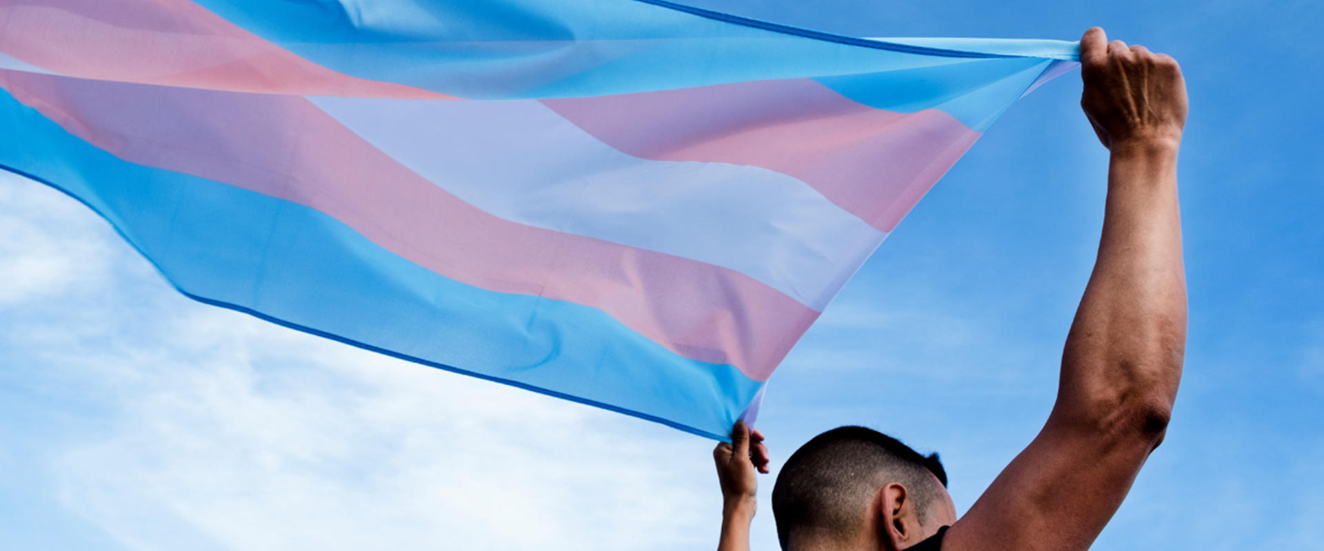 Man holding a pink, blue and white flag