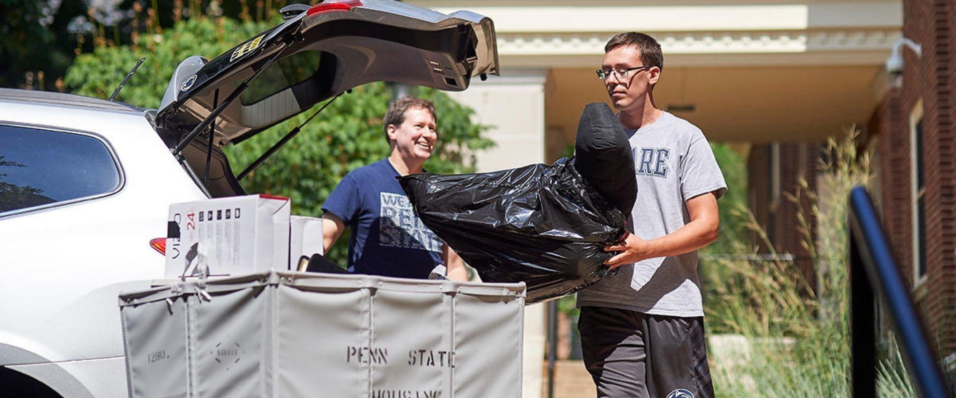 student unloading bags from car during move-in