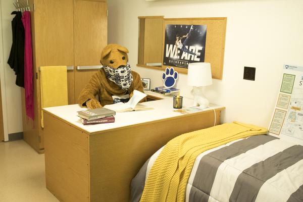 Nittany Lion masked and studying in a student room