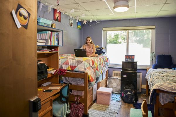 Student sitting on raised bed in her double room in Mont Alto Hall