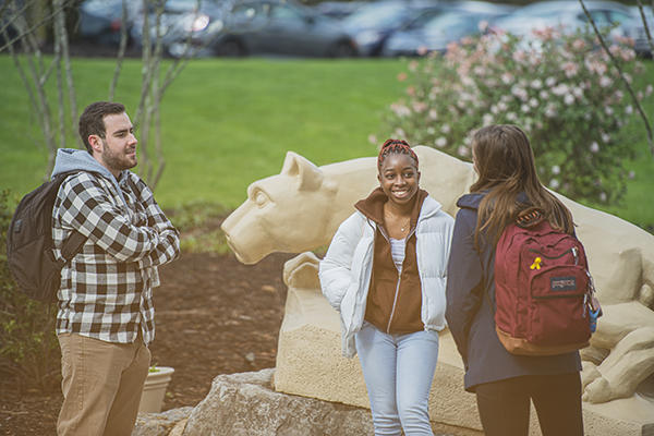 Students visiting on campus in front of the Nittany Lion shrine