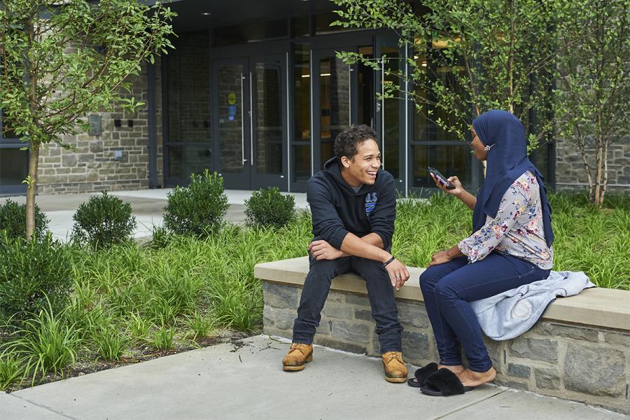 two students sitting on patio chatting