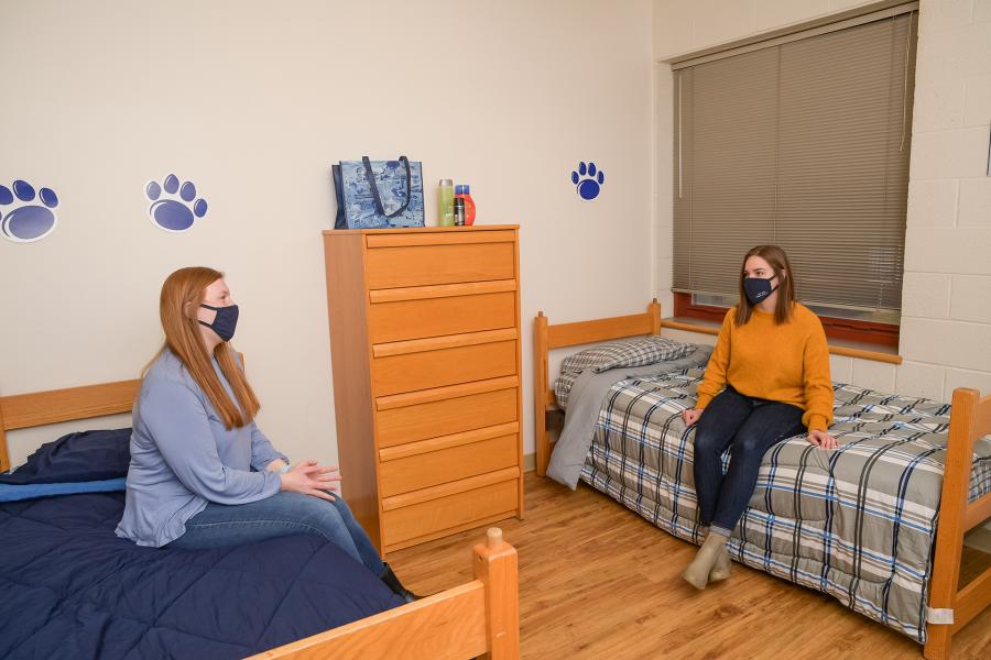 Two masked students sitting on beds in Ohio double room
