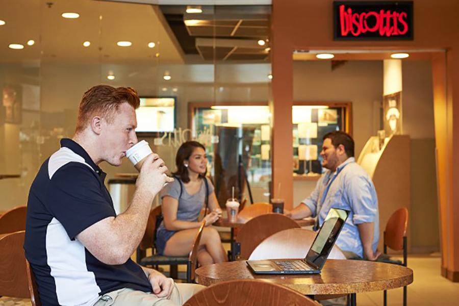 student drinks coffee in the seating are of biscotti's 