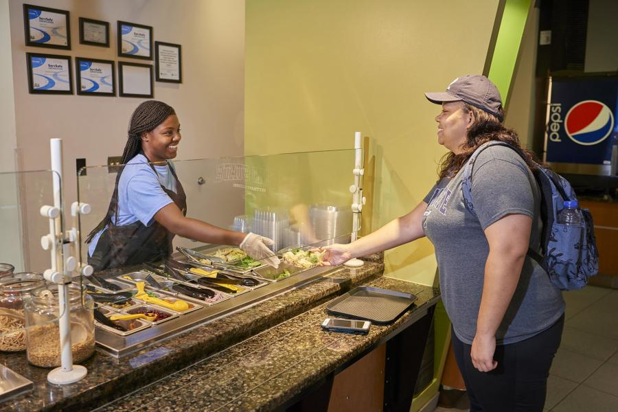 Student employee helping guest at Stacks salad station