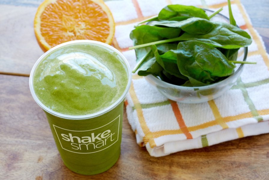 green smothie from Shakesmart with bowl of spinach and an orange
