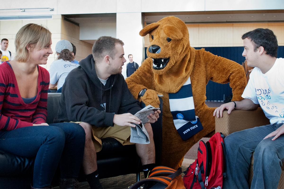 3 students talking with the Nittany Lion