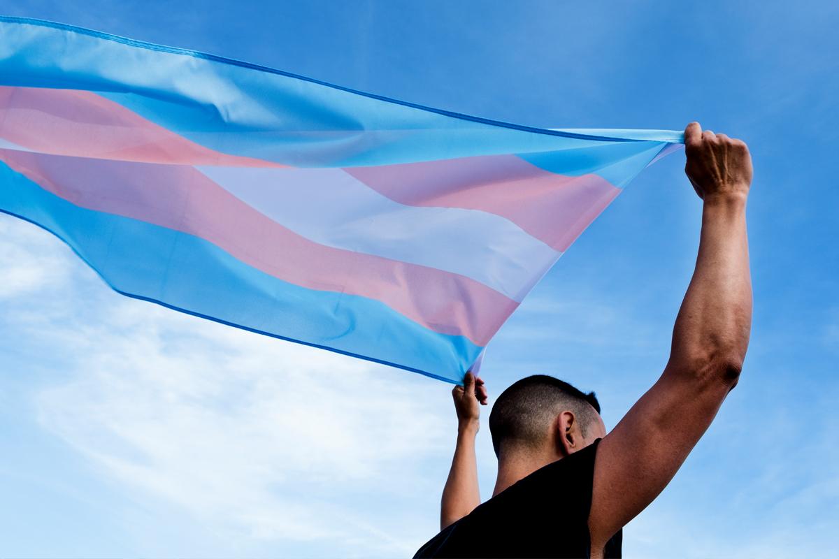Man holding a pink, blue and white flag