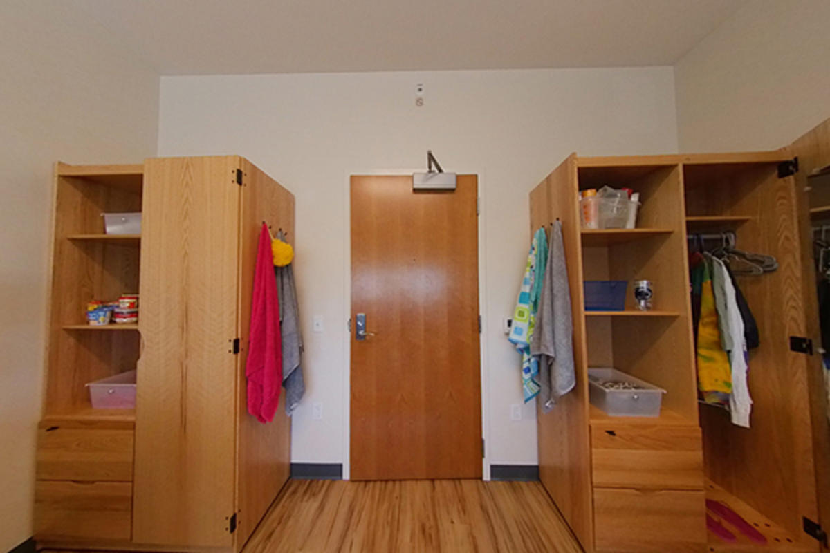 A well-organized dorm room with wooden furniture and storage.
