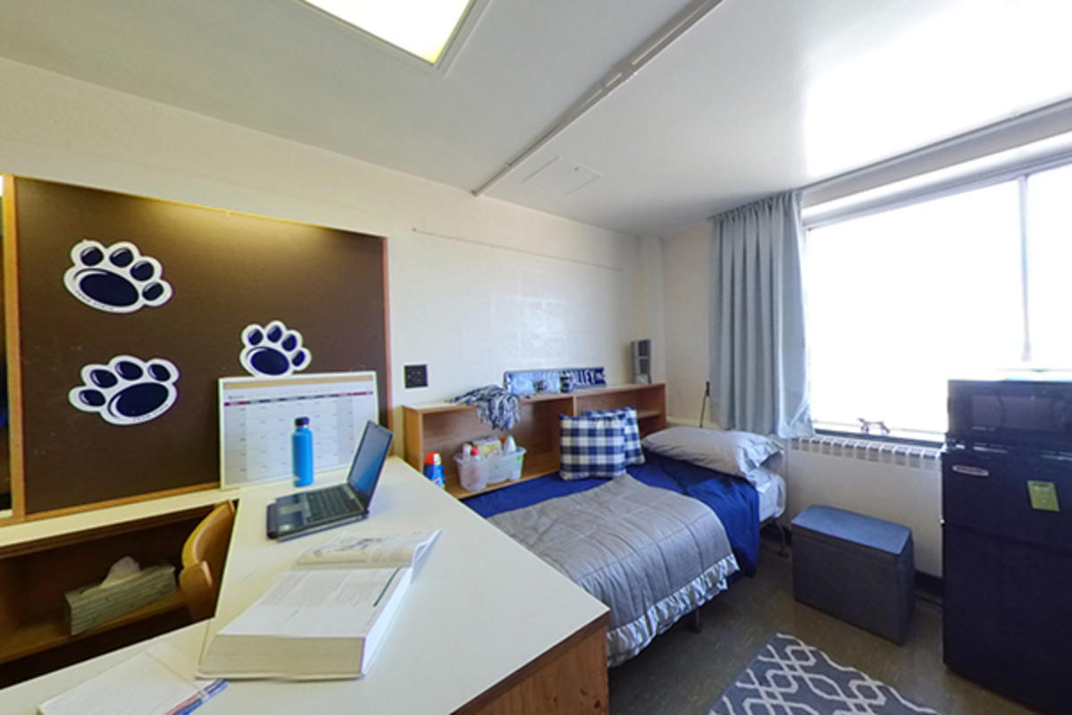 A neatly organized dorm room with a bed, furniture, appliances, and personal items.