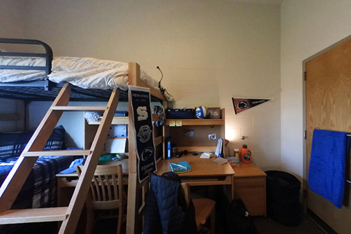 A neatly organized dorm room with wooden furniture and personal items.