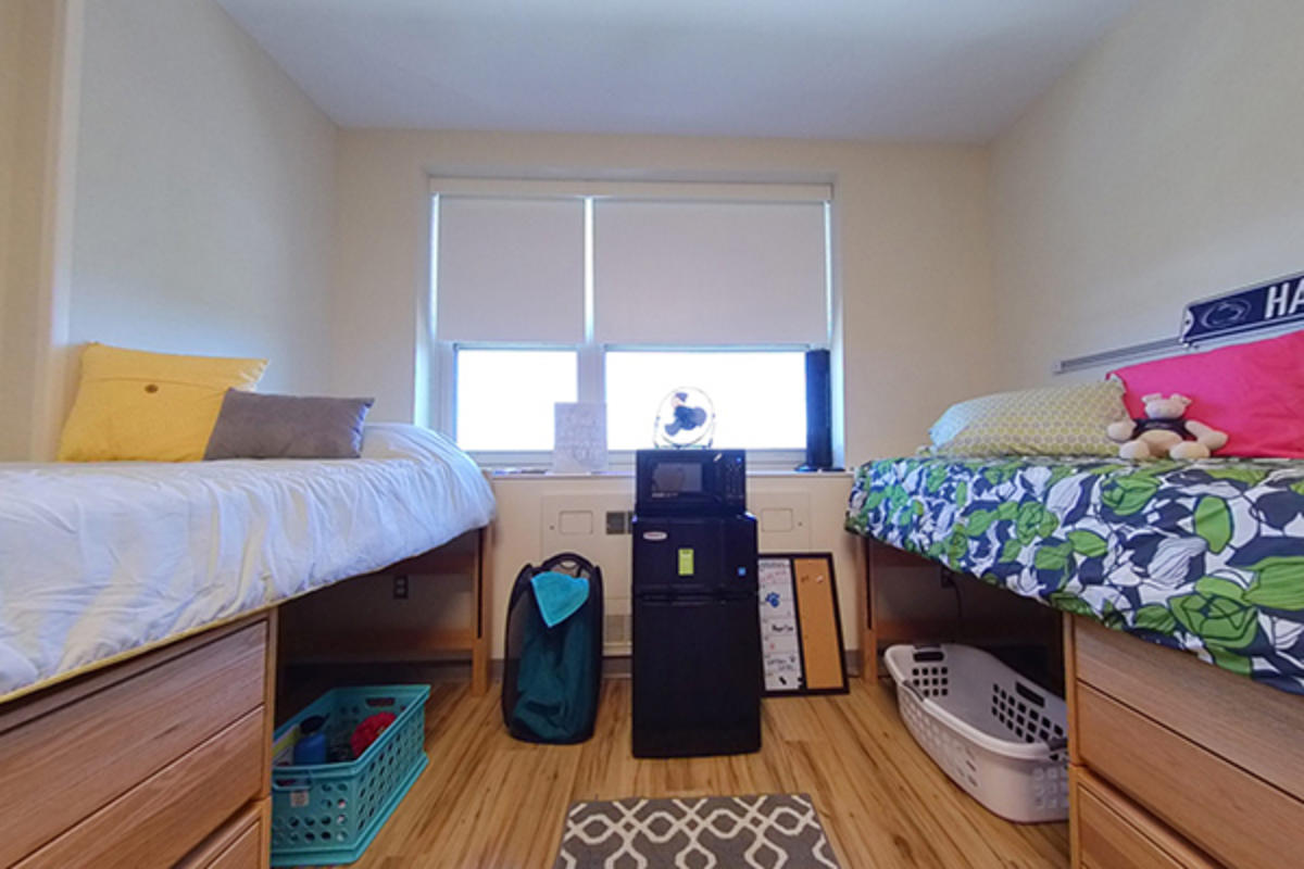 A neatly organized dorm room with two beds, appliances, and personal items.