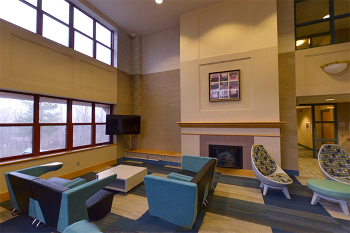 A modern, cozy lounge with a fireplace, seating, and large windows.