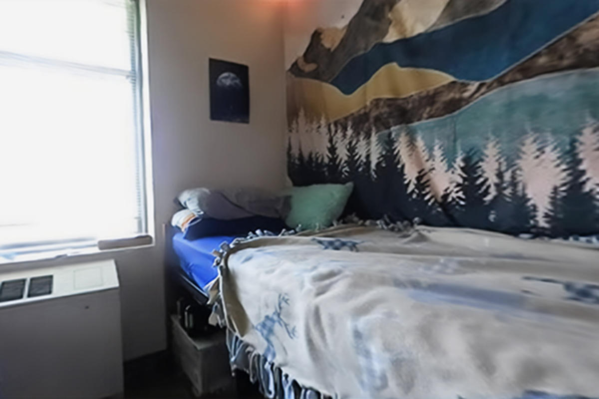 A tidy dorm room with a window and a made bed.