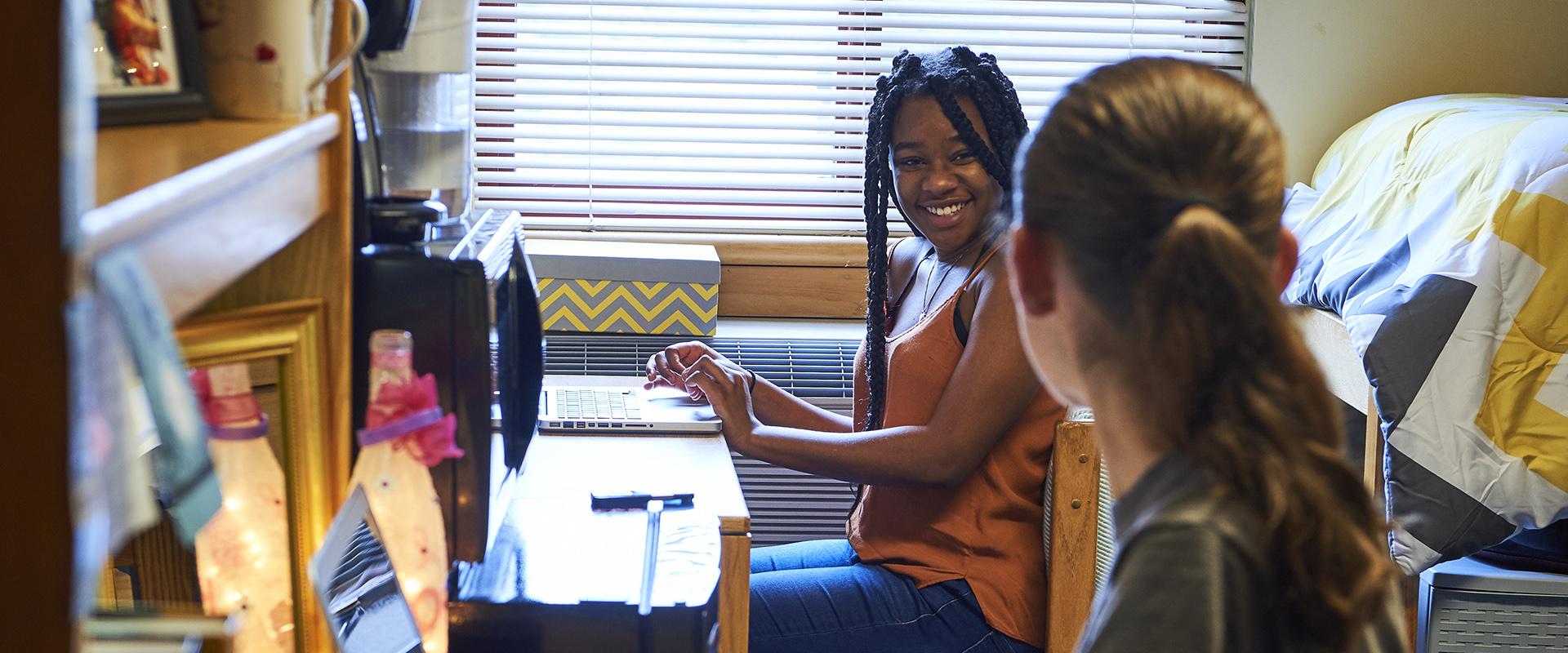 two smiling students sitting at desks in double room