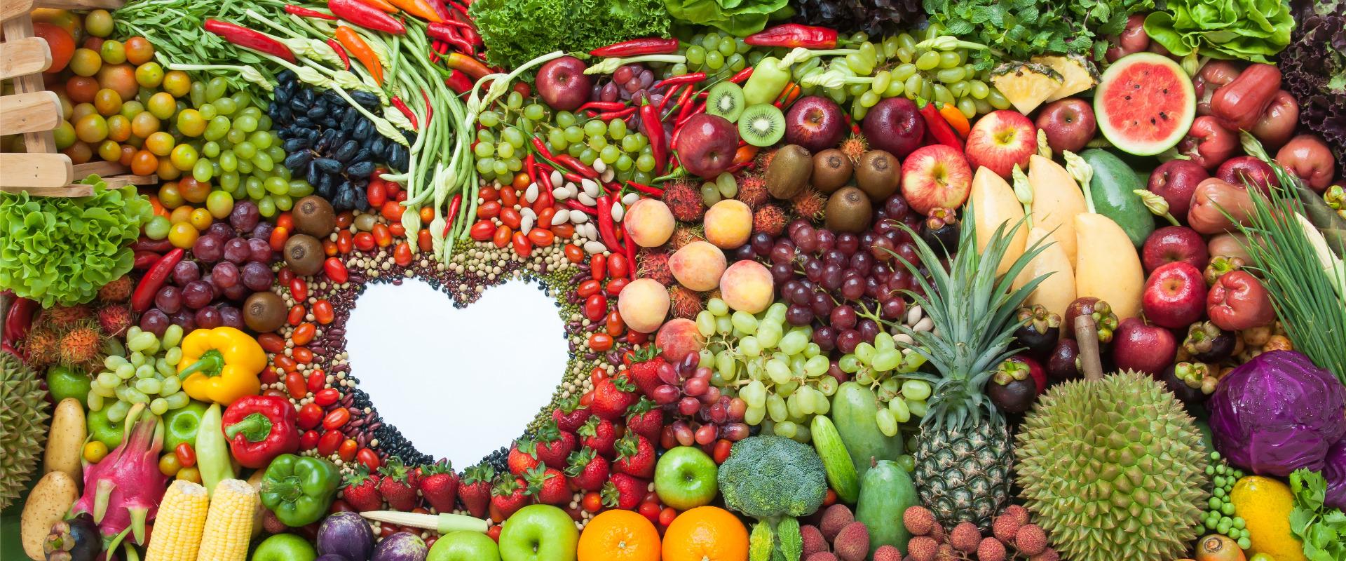 fruits veggies and nuts surrounding white space in shape of heart