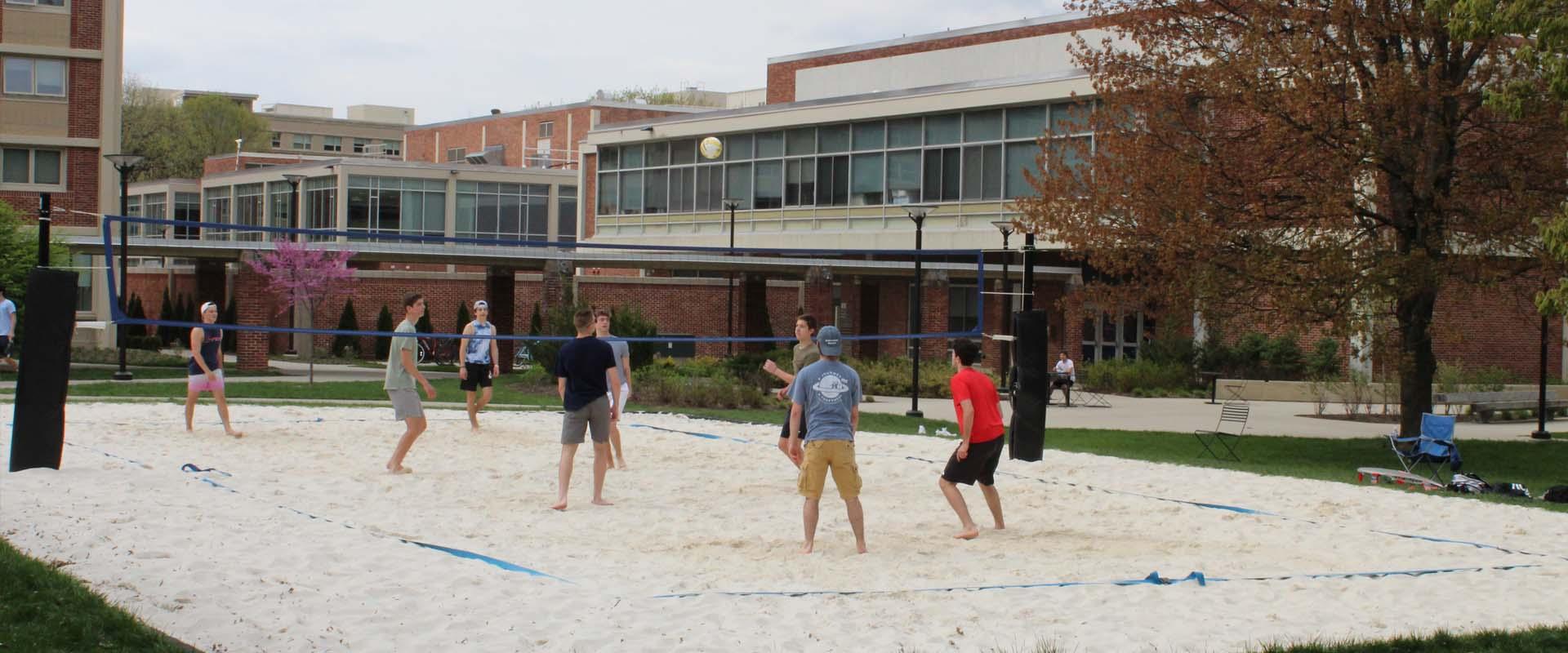 students playing sand volleyball in the residence quad