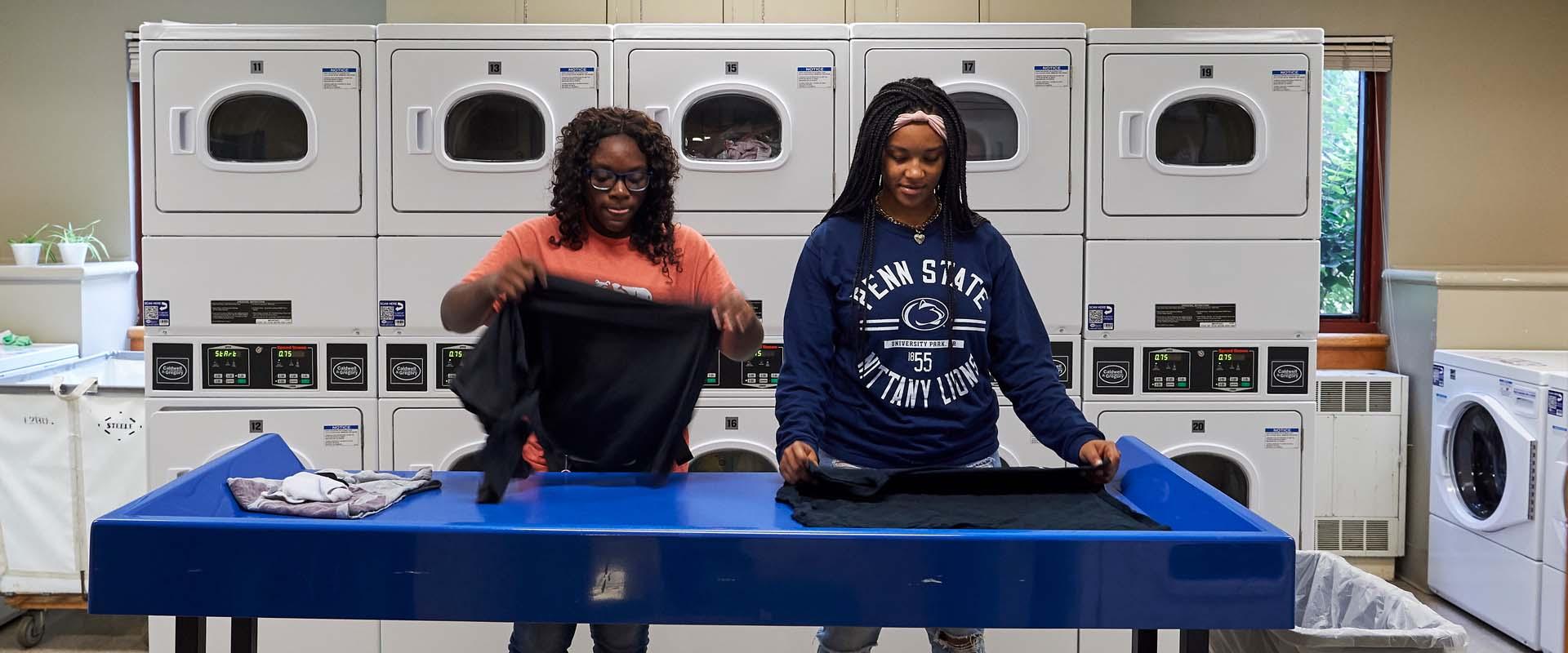 Two students folding laundry