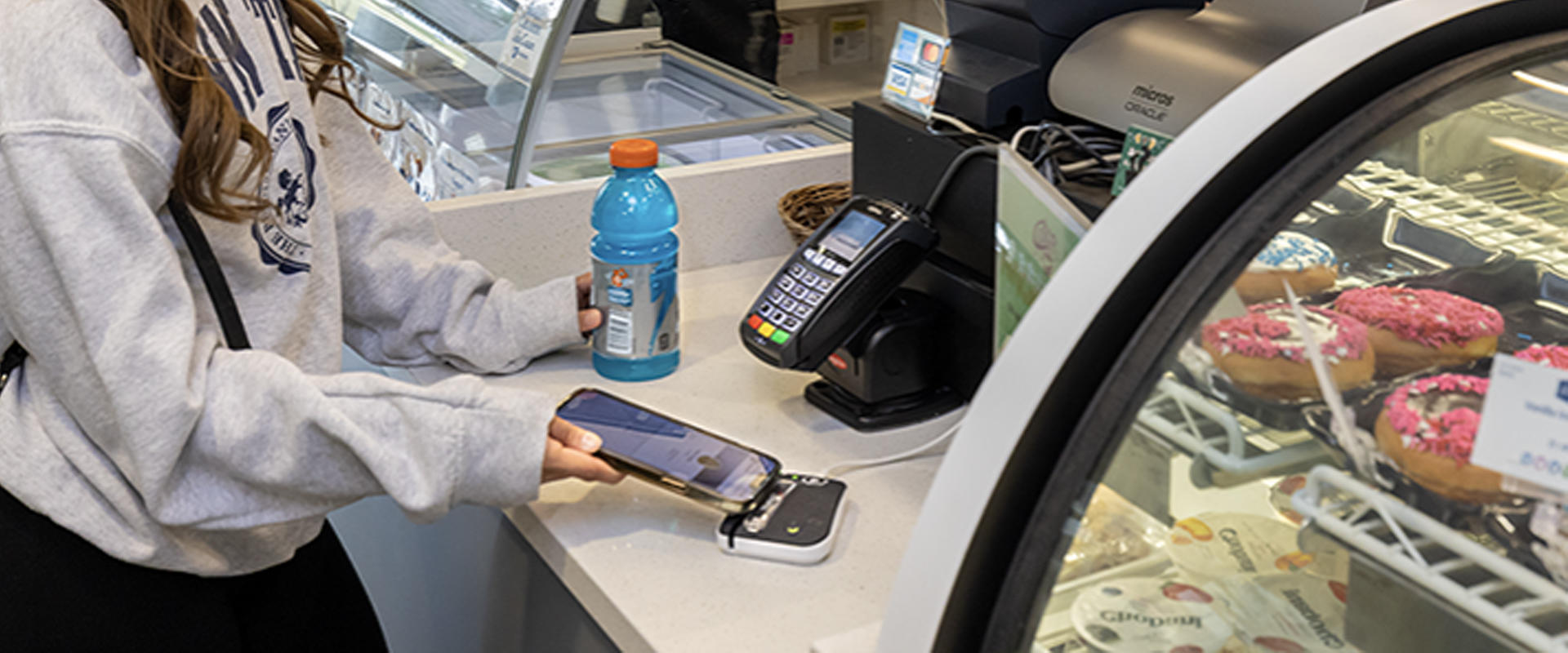 a student using her cell phone to tap and pay for a drink 