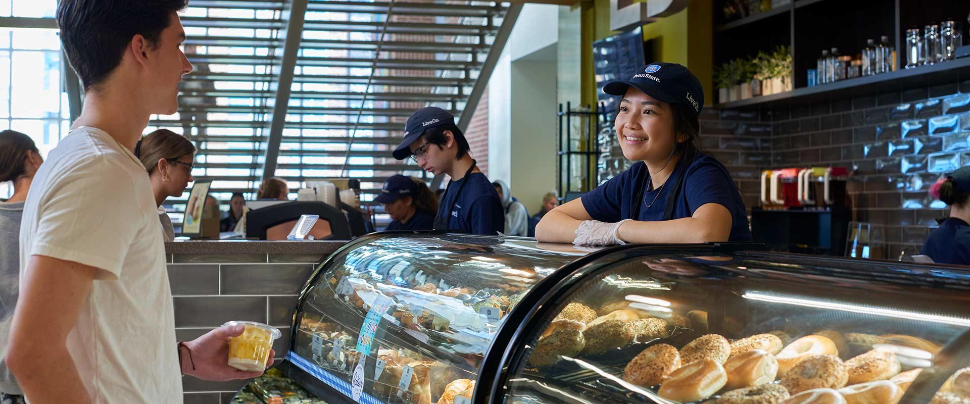 student employee interacts with customer at campus cafe