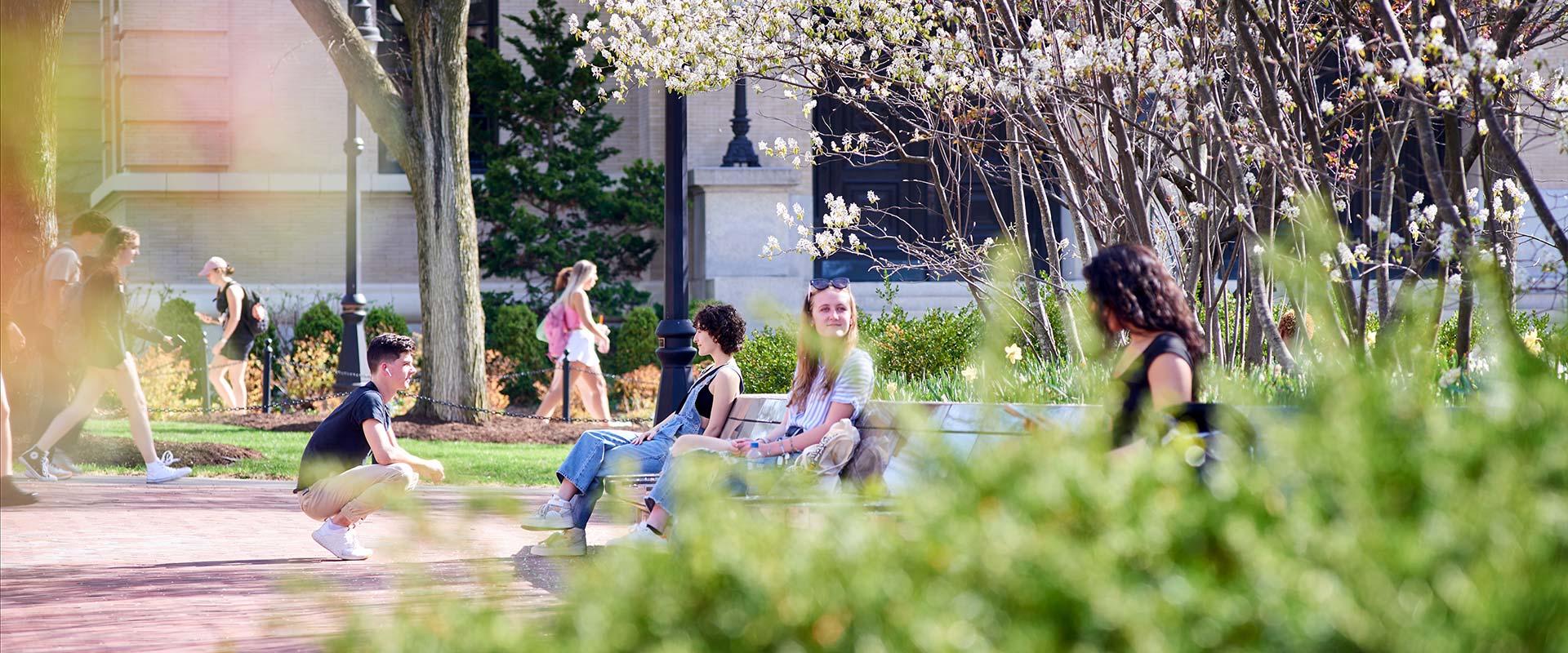 students visit between classes on the west side of campus