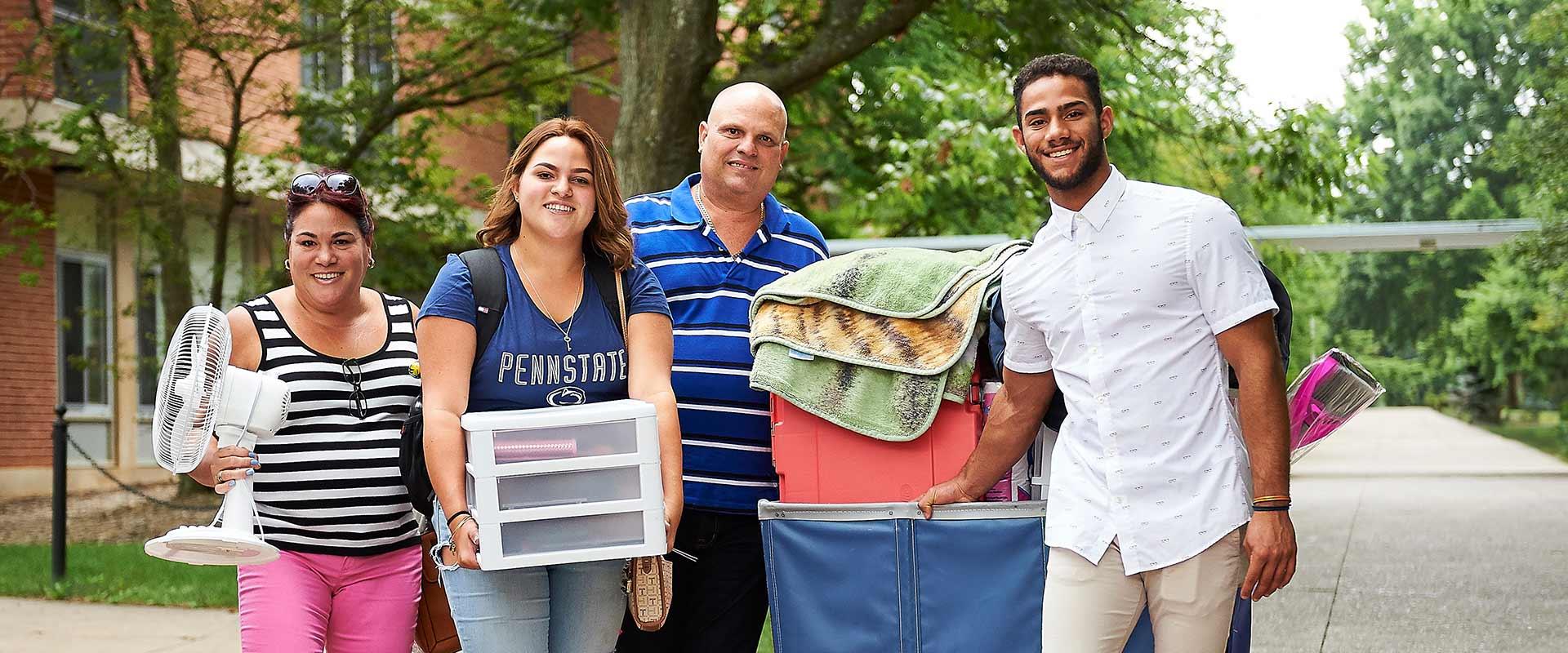 family poses with their belongings during arrival week