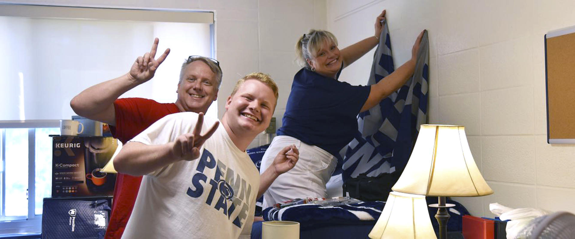 a family helps their student move into his residence hall room