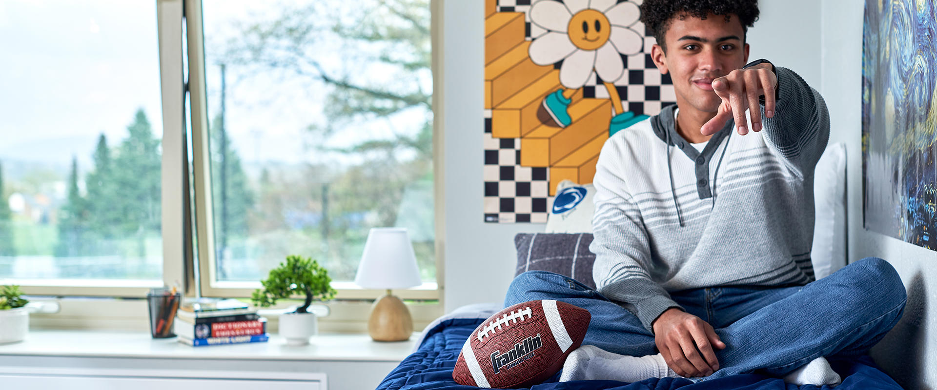 Student with football in residence hall room